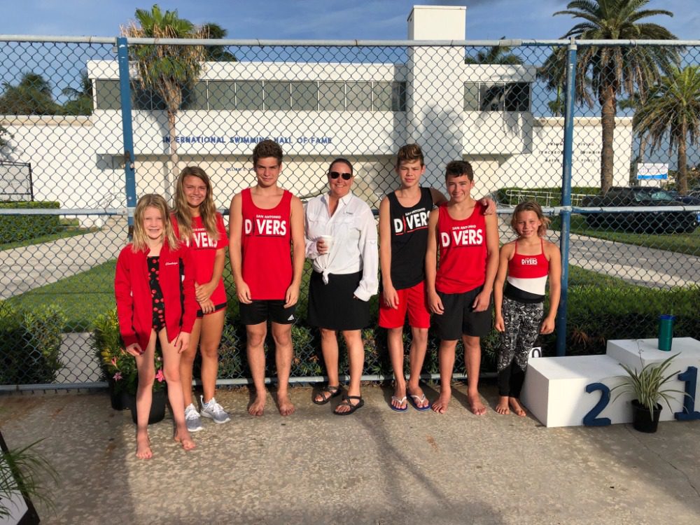 Competitive team members posing with coach Allison in front of the awards stand.